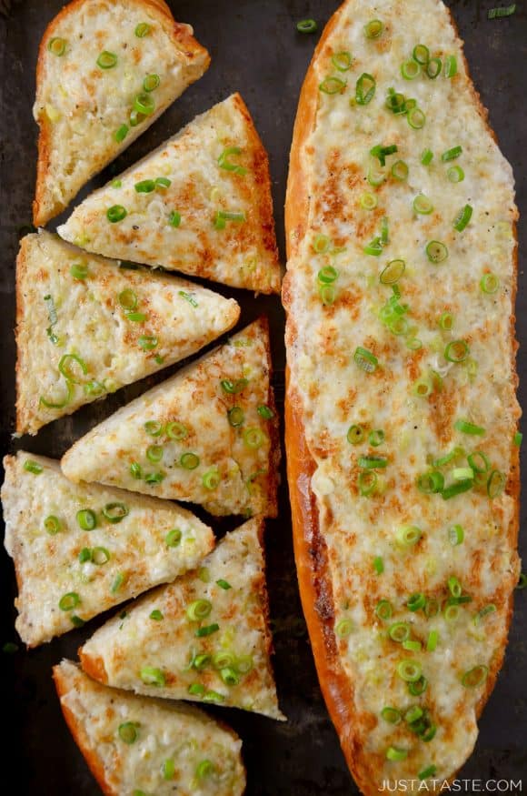 A baking sheet containing a loaf of garlic bread cut into triangles