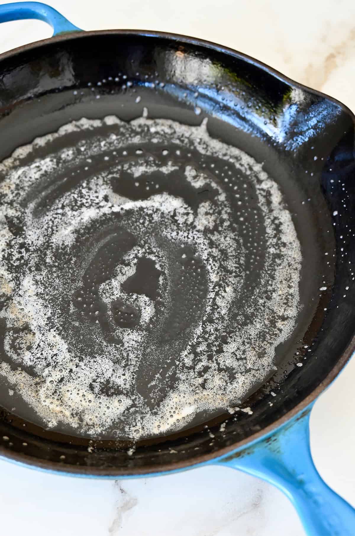 A cast iron skillet coated with melted butter.