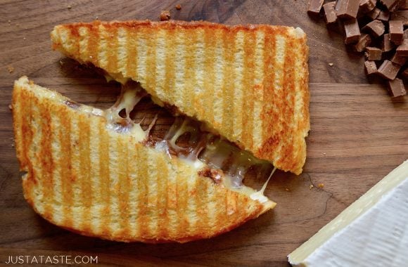 A chocolate and brie panini sandwich cut in half on a wood cutting board