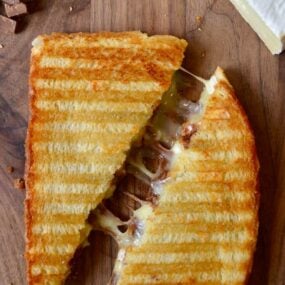 A Chocolate and Brie Panini sandwich on a wood cutting boar