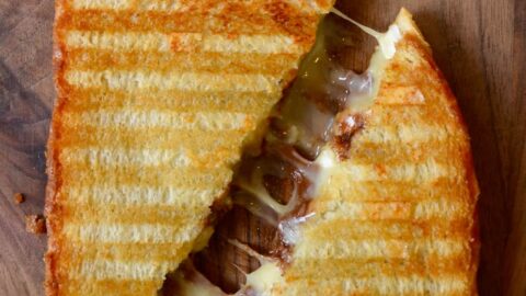 A Chocolate and Brie Panini sandwich on a wood cutting boar