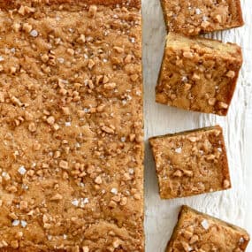 A top-down view of toffee blondies topped with toffee bits and large-flake sea salt.