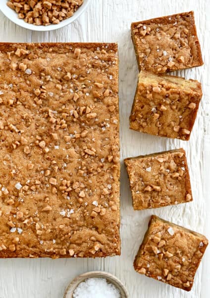 A top-down view of toffee blondies topped with toffee bits and large-flake sea salt.
