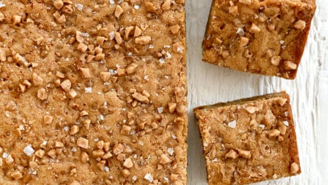 A top-down view of toffee blondies topped with toffee bits and large-flake sea salt.
