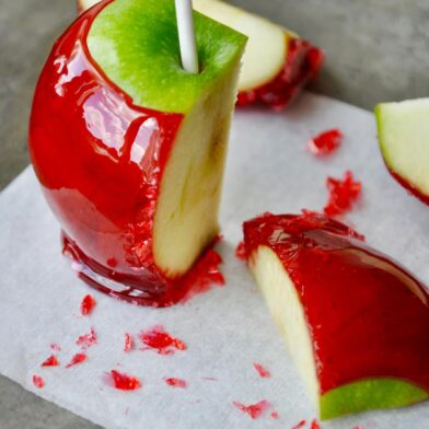 A green candy apple sliced on a grey baking sheet