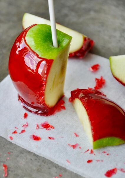 A green candy apple sliced on a grey baking sheet