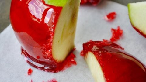 A green candy apple sliced on a grey baking sheet