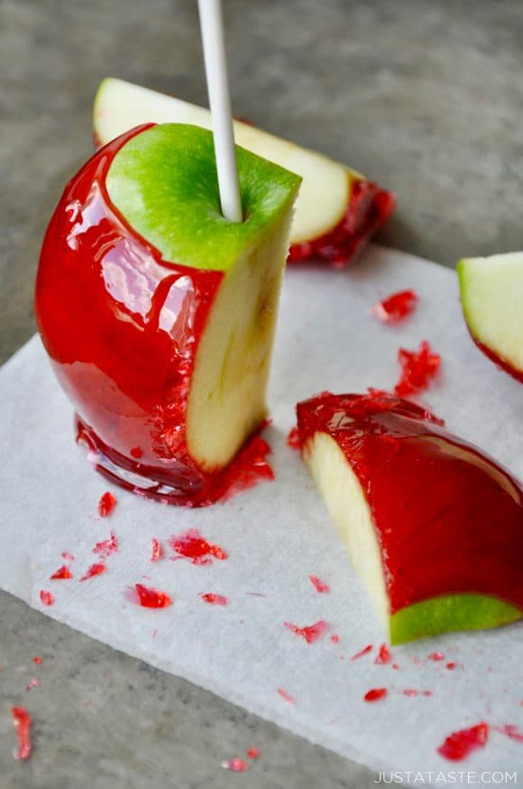 A green candy apple sliced on a grey baking sheet