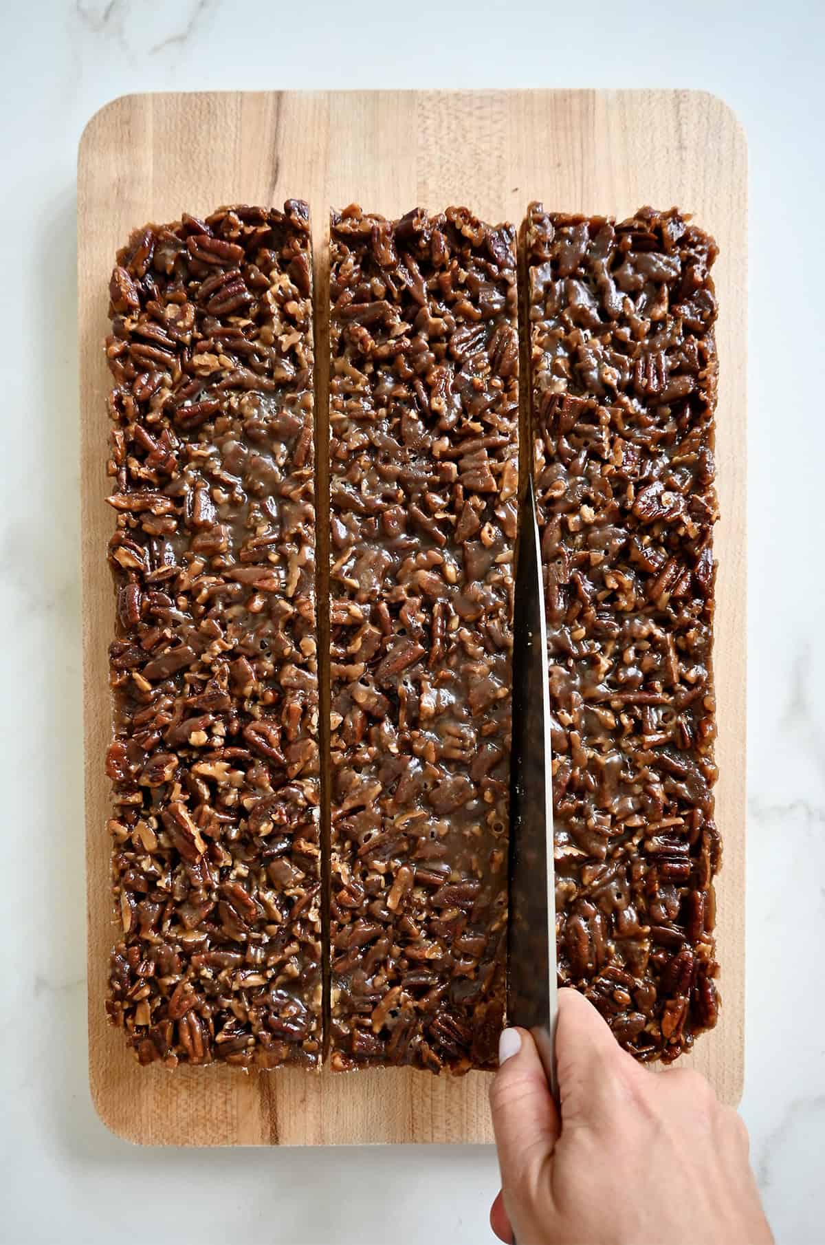 Cutting pecan pie bars into squares with a sharp knife.
