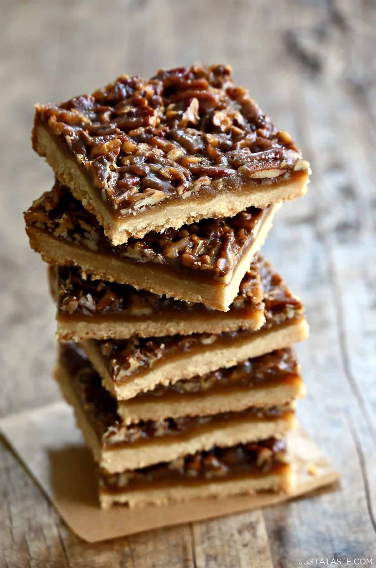 Pecan pie bars stacked seven high on a square of parchment paper.