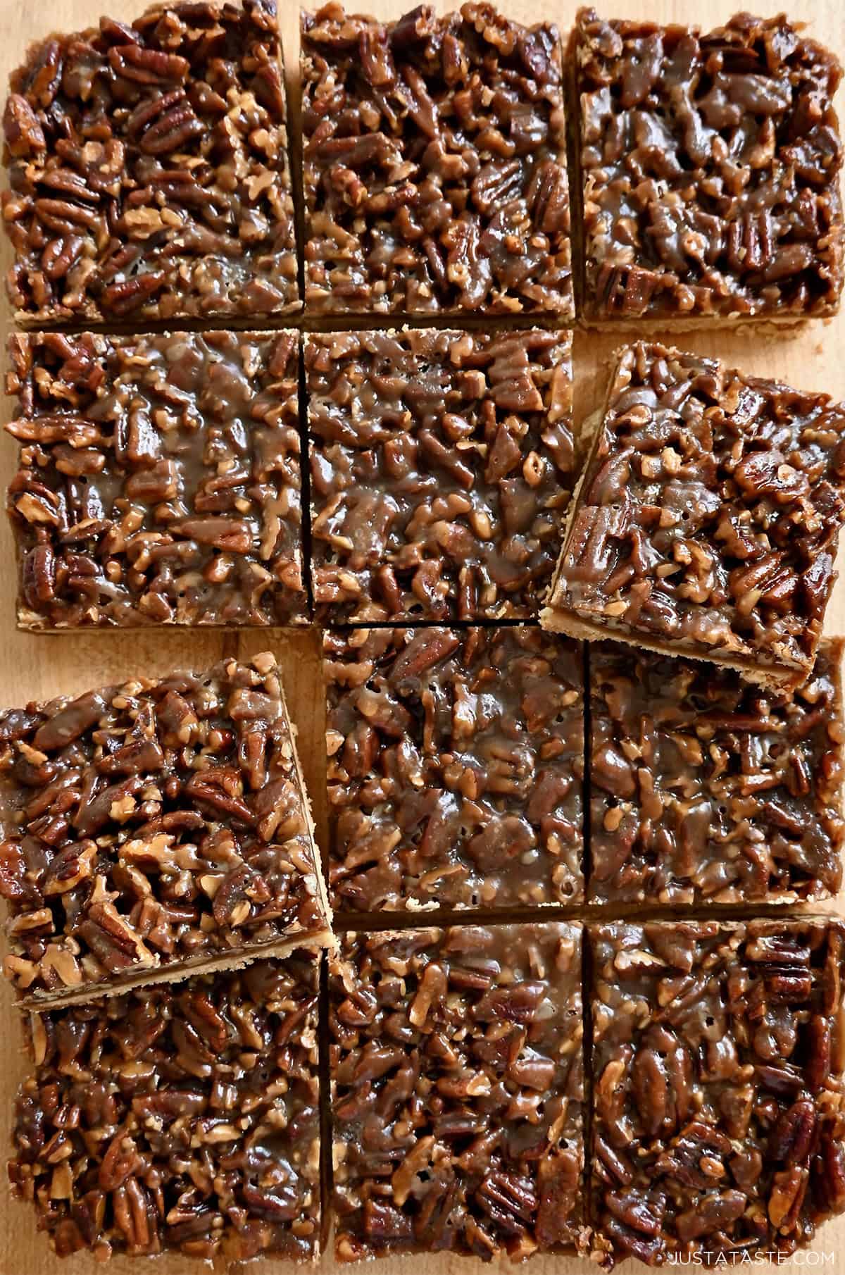 Pecan pie squares with a semi-soft shortbread cookie base and a chewy pecan pie topping on a wooden surface.
