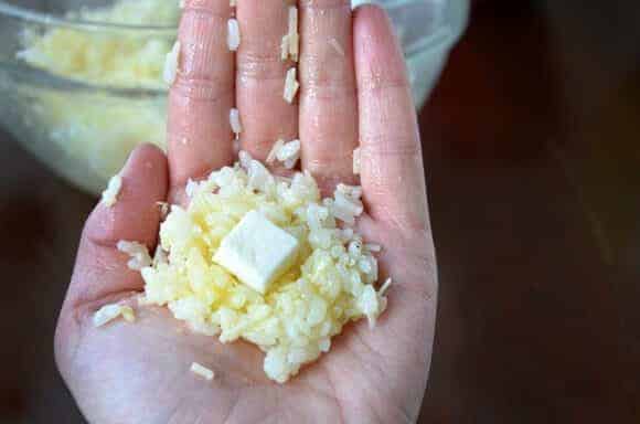 Open hand with arancini mixture topped with mozzarella