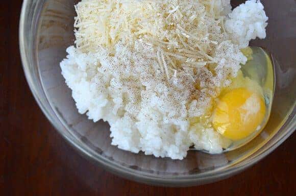 Rice, parmesan cheese and an egg in a clear bowl