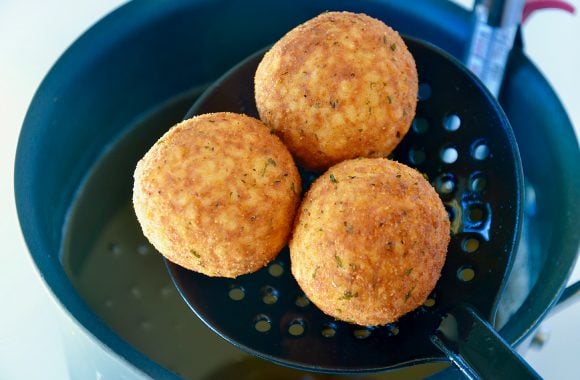 Slotted spoon with fried arancini rice balls