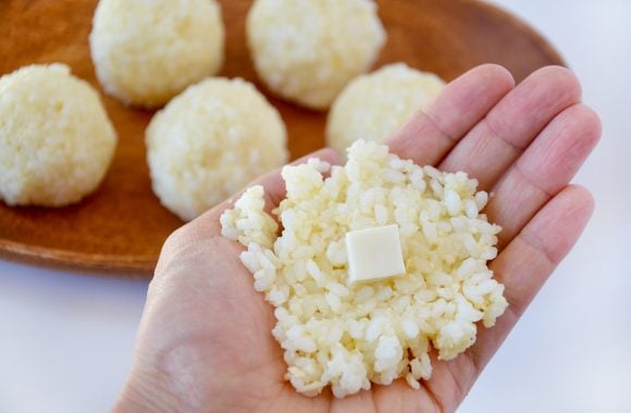 Hand with rice and mozzarella cheese to form arancini ball