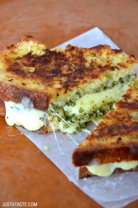 An Irish soda bread grilled cheese sandwich with cheddar and pesto sits on a sheet of white parchment paper.