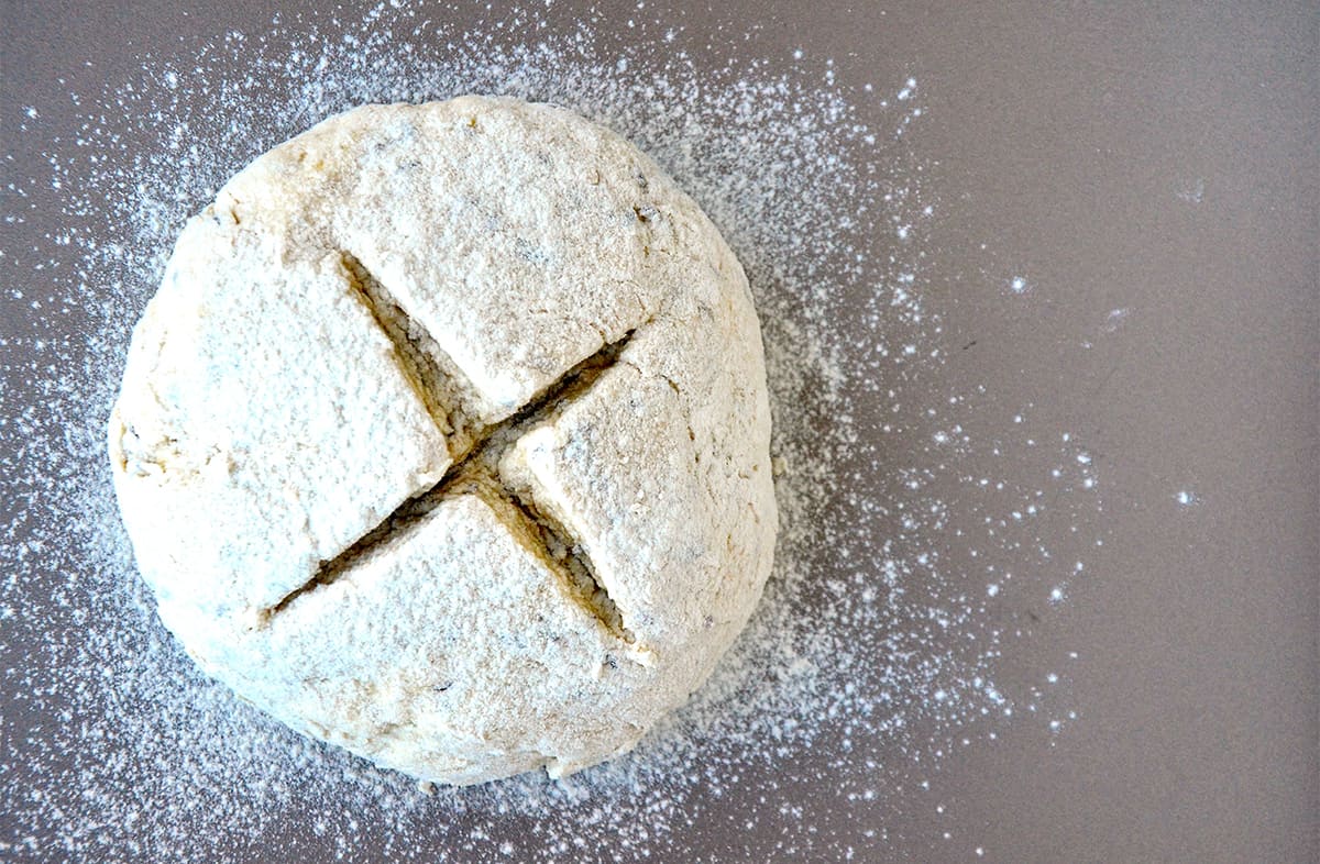 Unbaked soda bread with a deep "X" cut into the center.