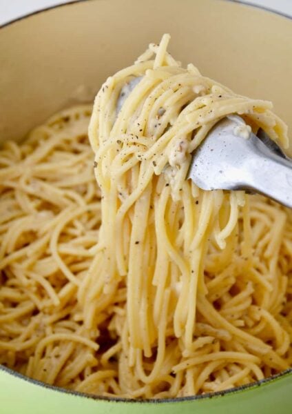 A green pot containing Cacio e Pepe Pasta and tongs