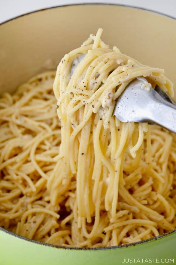 A green pot containing Cacio e Pepe Pasta and tongs