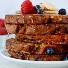 Stack of Banana Bread French Toast topped with fresh fruit and pure maple syrup