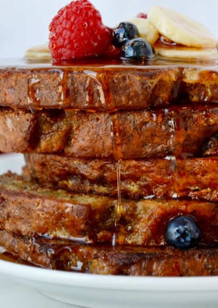 Stack of Banana Bread French Toast topped with fresh fruit and pure maple syrup