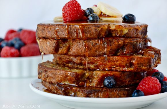 Stack of Banana Bread French Toast topped with fresh fruit and pure maple syrup