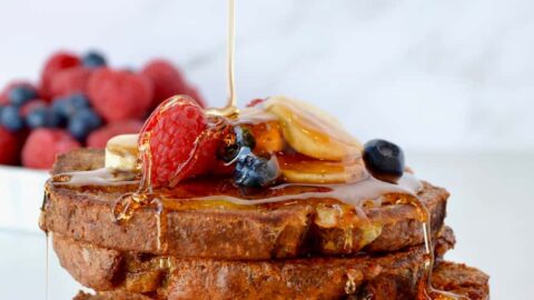 Stack of Banana Bread French Toast with maple syrup drizzle and fresh fruit
