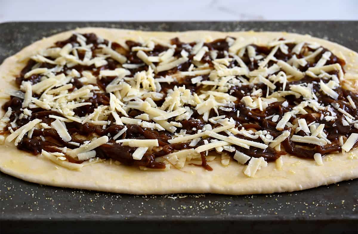 Pizza dough topped with balsamic caramelized onions and shredded gruyere cheese.