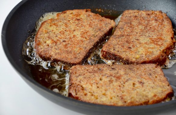 Three pieces of Banana Bread French toast frying in pan