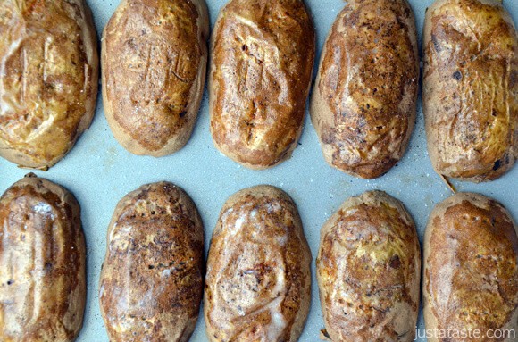 Baked, scooped out potatoes cut side down on a baking sheet.