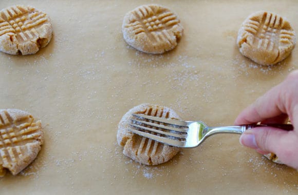 Hand with fork pressing down on peanut butter cookie dough