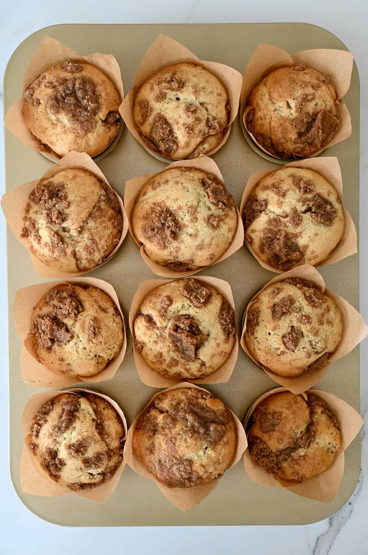 Freshly baked crumb cake muffins in a muffin pan.