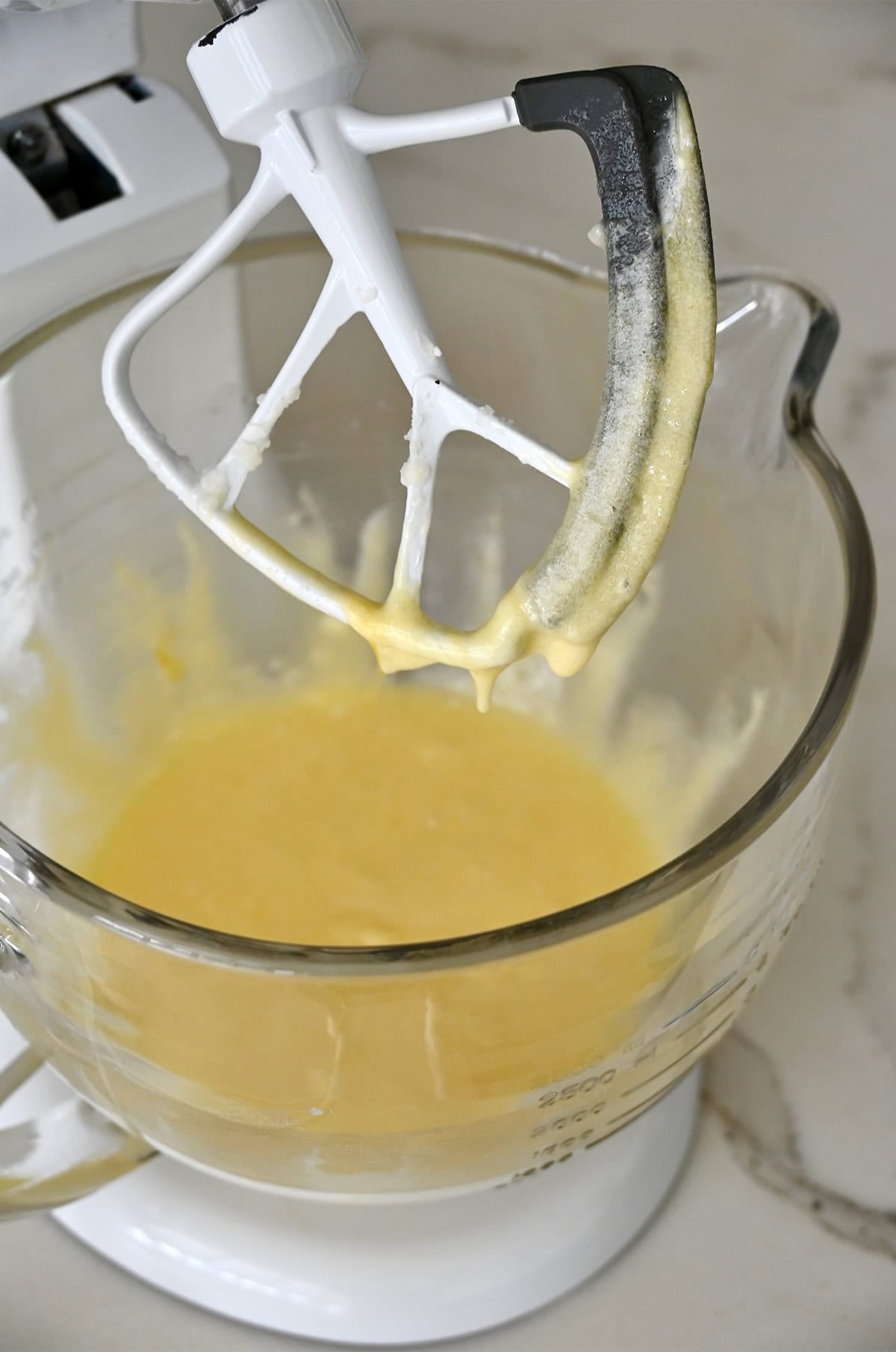 A stand mixer bowl containing creamed butter, oil and sugar.