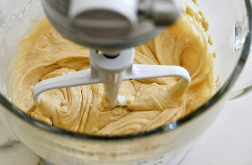 A clear stand mixer bowl containing batter