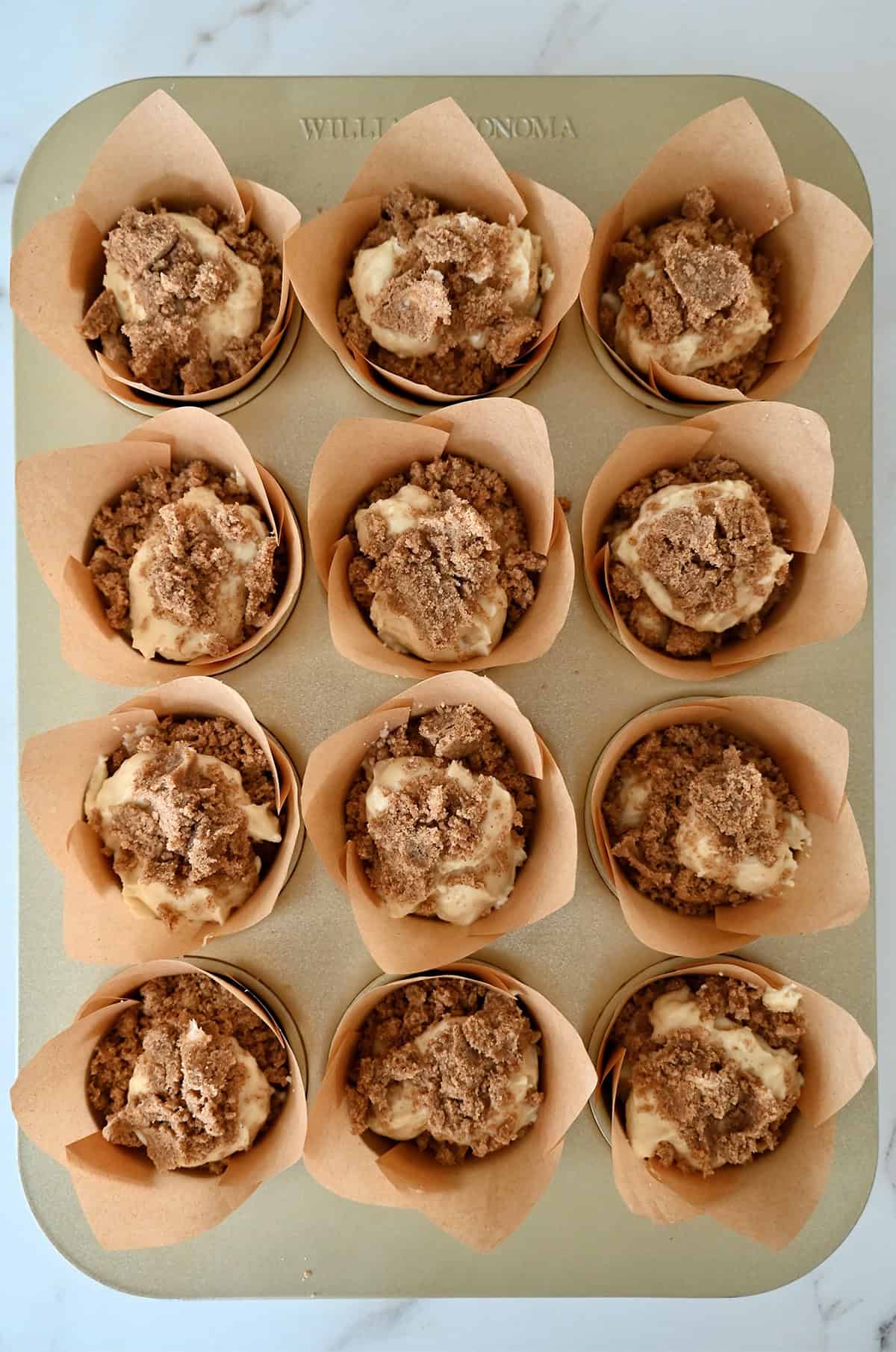 Unbaked vanilla coffee cake muffins with crumb topping.