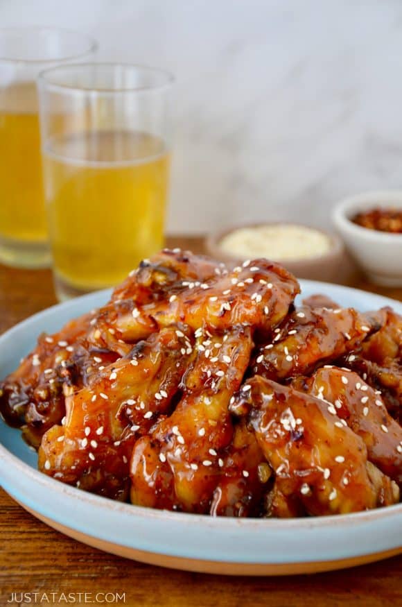 Crispy Baked Orange Chicken Wings on pale blue plate with two glasses of beer in background.