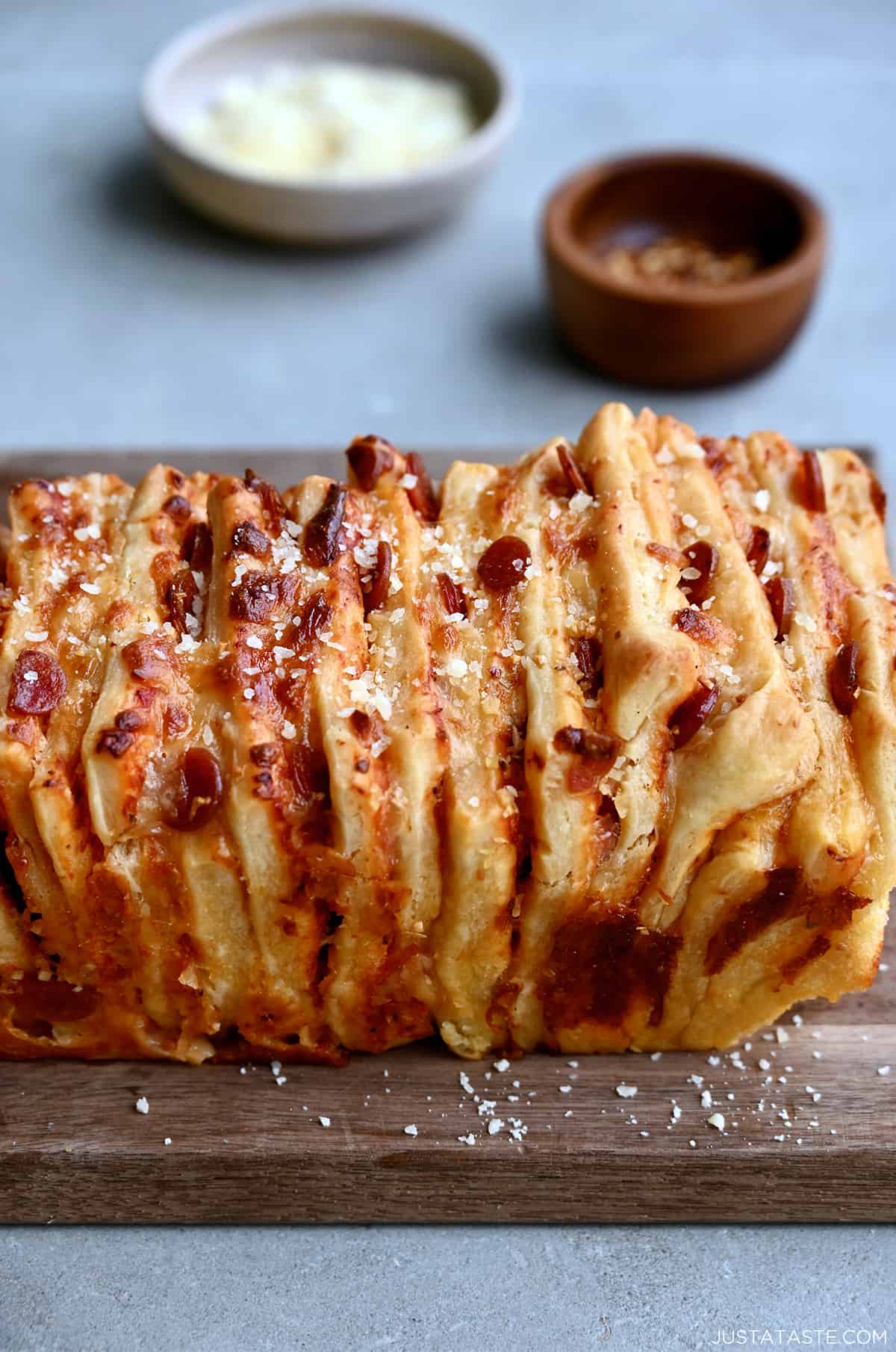 Pizza pull-apart bread with mini pepperoni garnished with grated parmesan cheese on a cutting board.