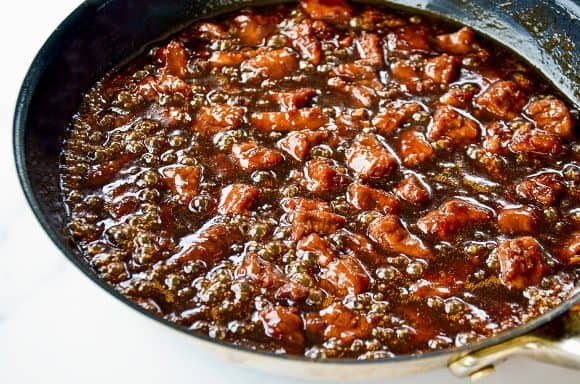 Skillet containing flank steak and Mongolian sauce