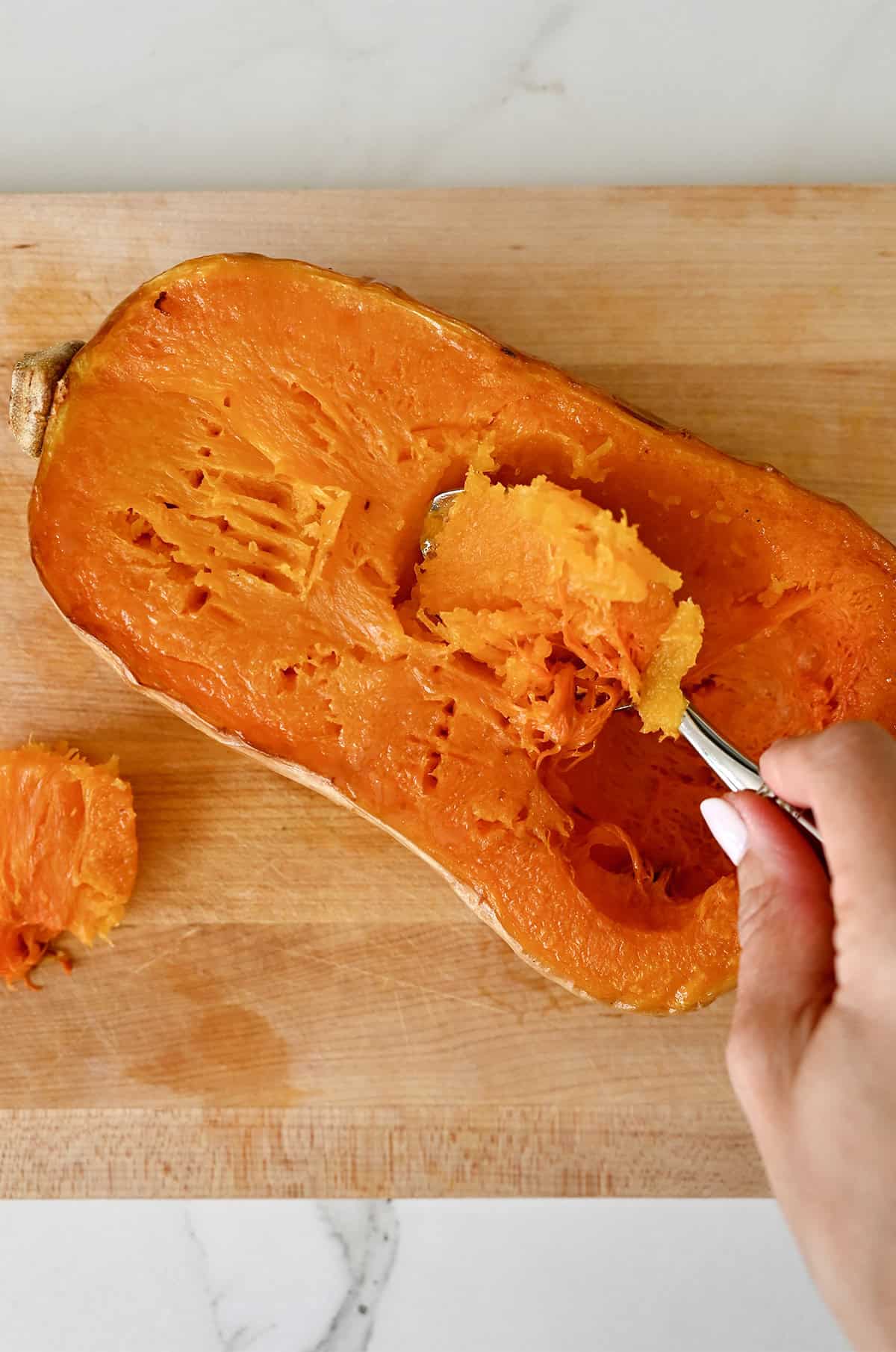 Scooping out the tender flesh of a roasted butternut squash half.