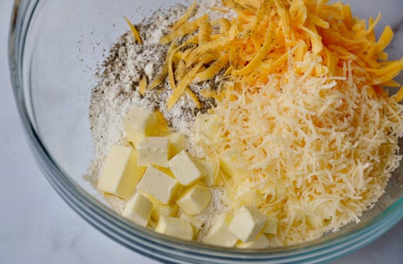 A glass bowl with flour, butter and shredded cheese for making biscuits
