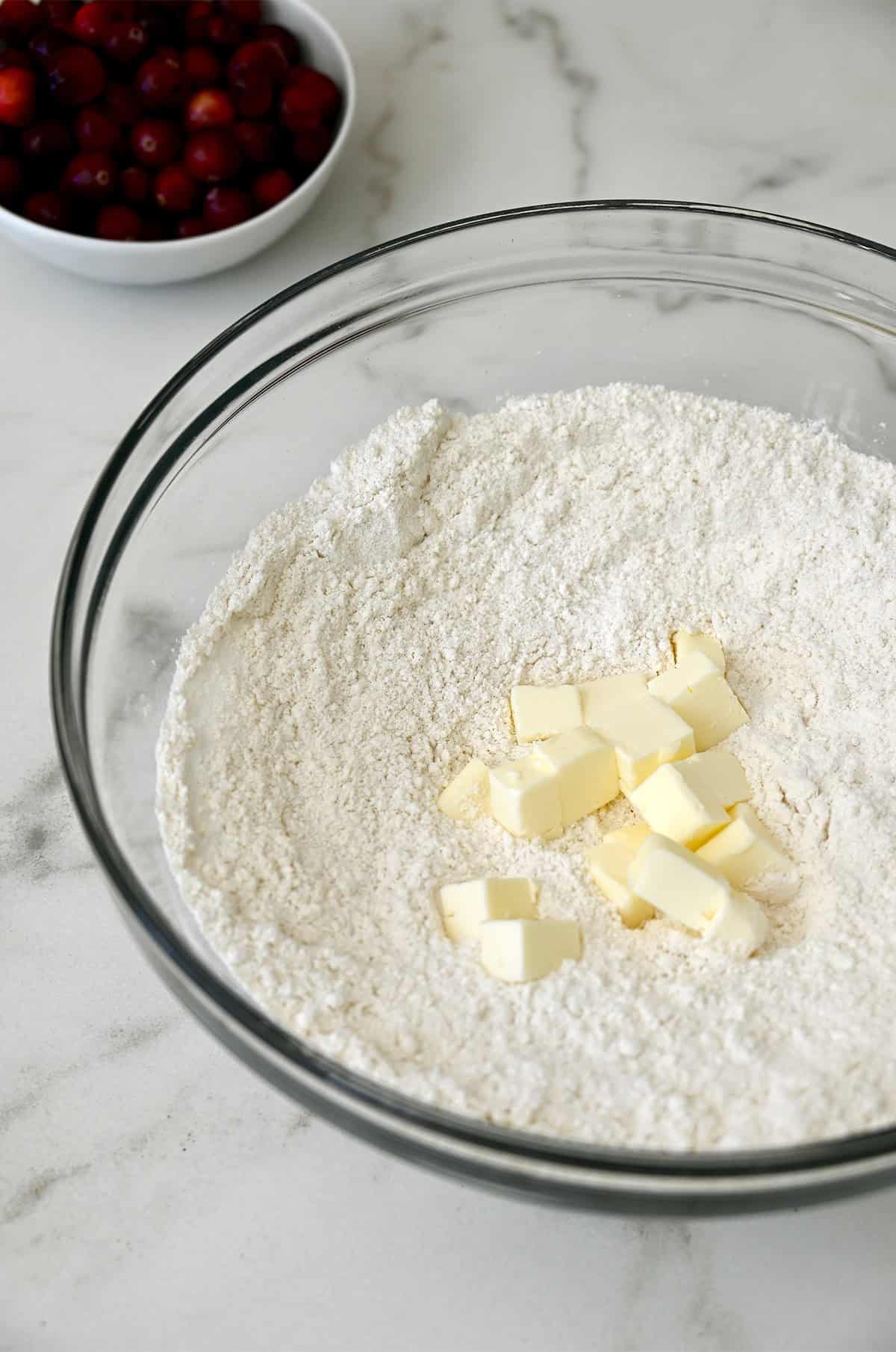 Cold, cubed butter atop flour in a glass bowl.