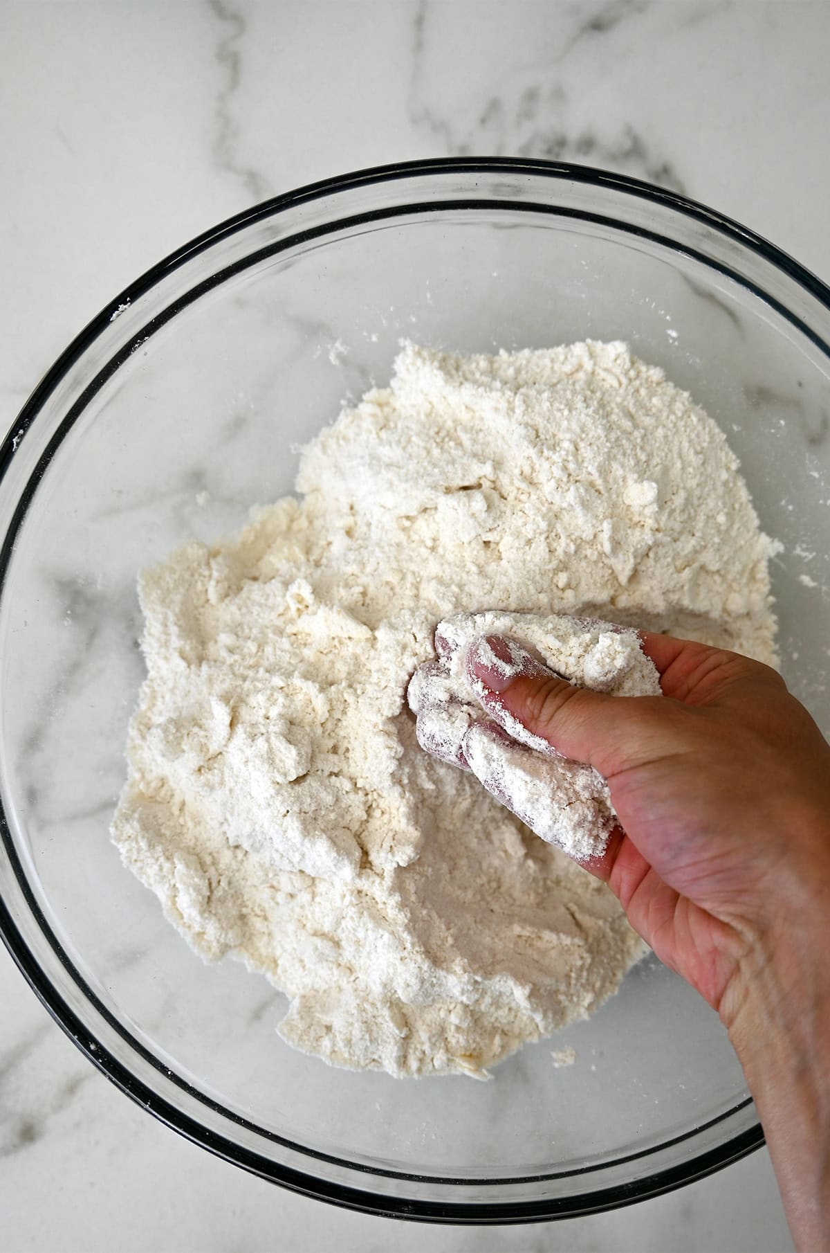 Hands cut butter into flour.
