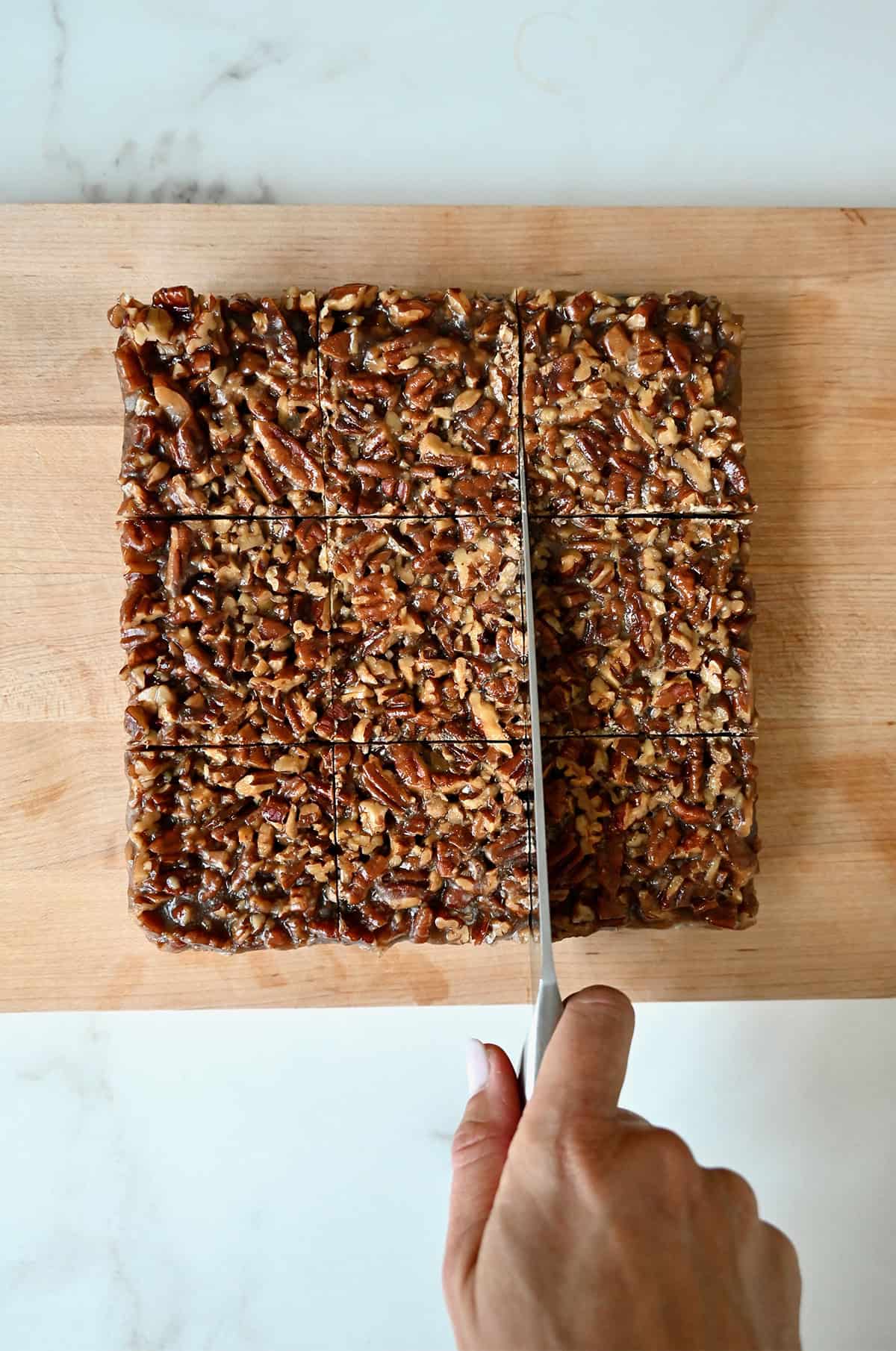 Cutting brownies with a pecan pie topping into squares.