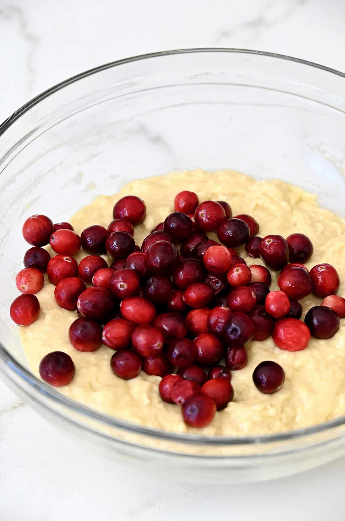 Fresh cranberries atop a quick bread batter in a bowl.