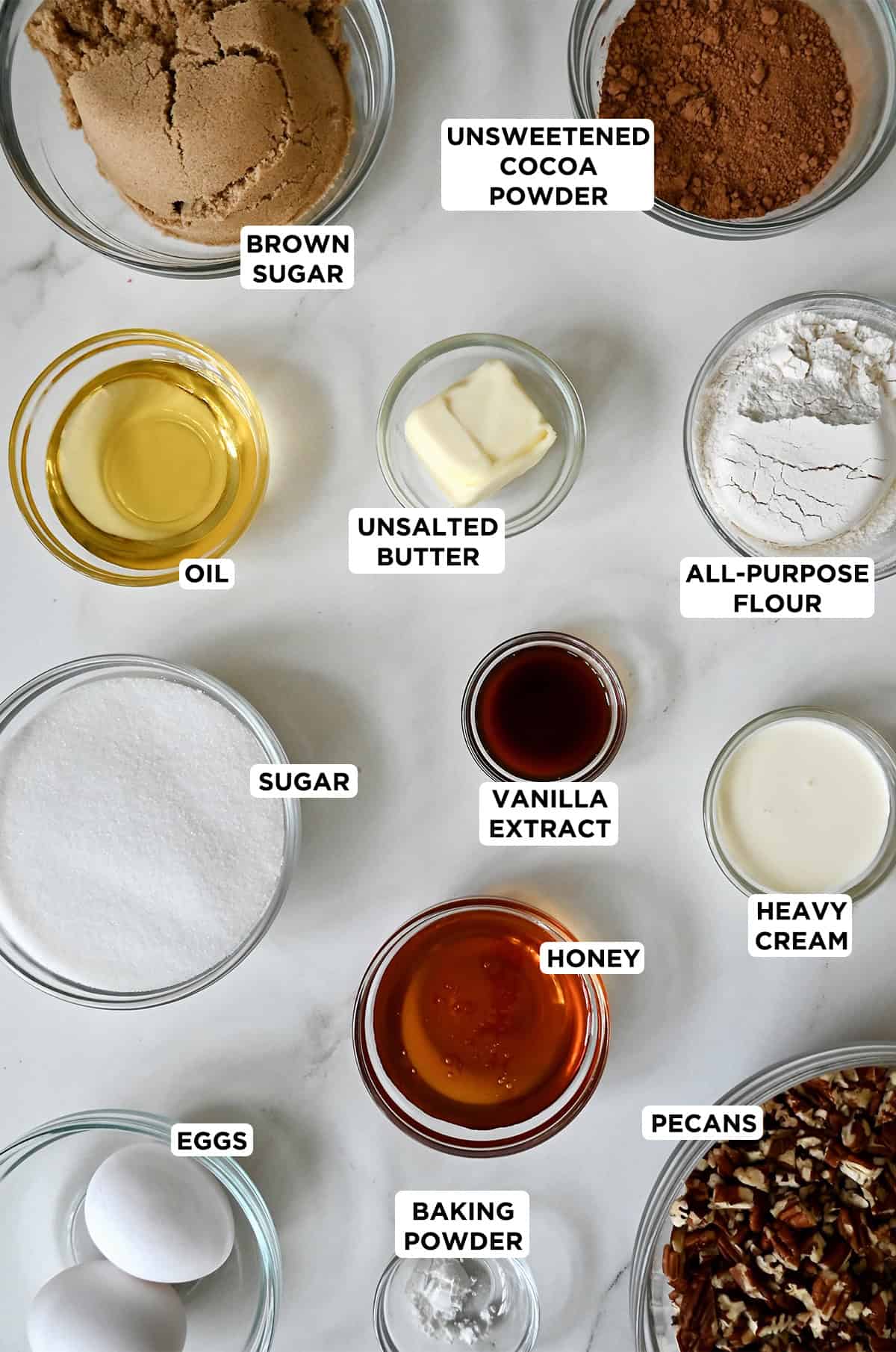 Ingredients to make brownies with a honey pecan topping in various sizes of glass bowls.