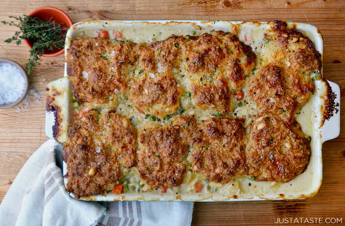 A baking dish with turkey pot pie and a towel and small dishes filled with herbs and salt