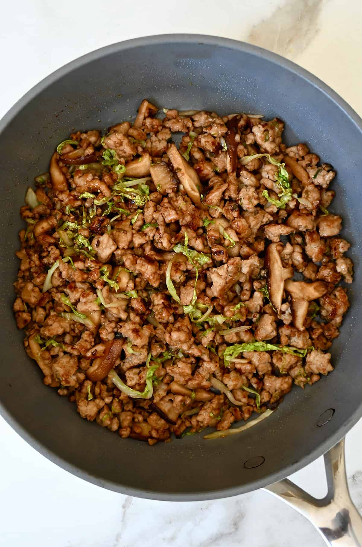 Sautéed chicken with cabbage, shiitake mushrooms and hoisin sauce in a large skillet.