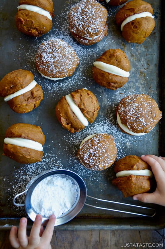 A baking sheet with whoopie pies and little kids' hands grabbing them