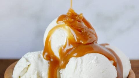Easy Homemade Butterscotch Sauce poured over vanilla ice cream in wooden bowl