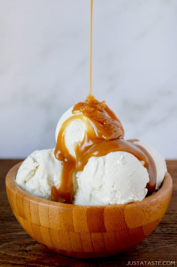 Easy Homemade Butterscotch Sauce poured over vanilla ice cream in wooden bowl